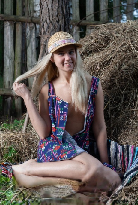 Young blonde Agnes H doffs a dress to get naked on weathered straw in a yard 81197802